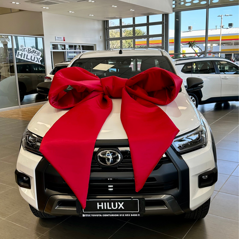 White Toyota Hilux with a extra large red bow in a showroom