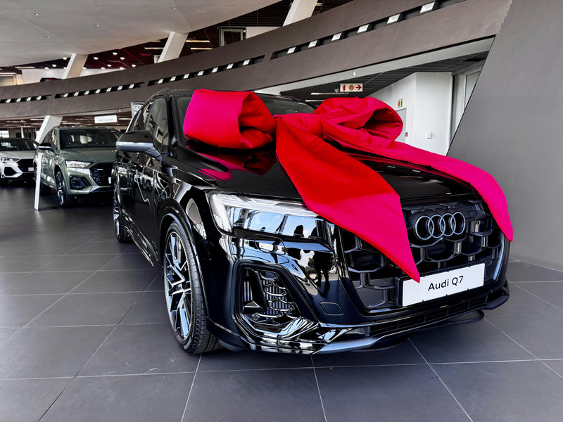 Black Audi Q7 with a large red bow in a showroom